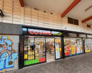 Cosmo Shop storefront on Xavier Nogués, with black fascia and stocked windows beneath a covered arcade